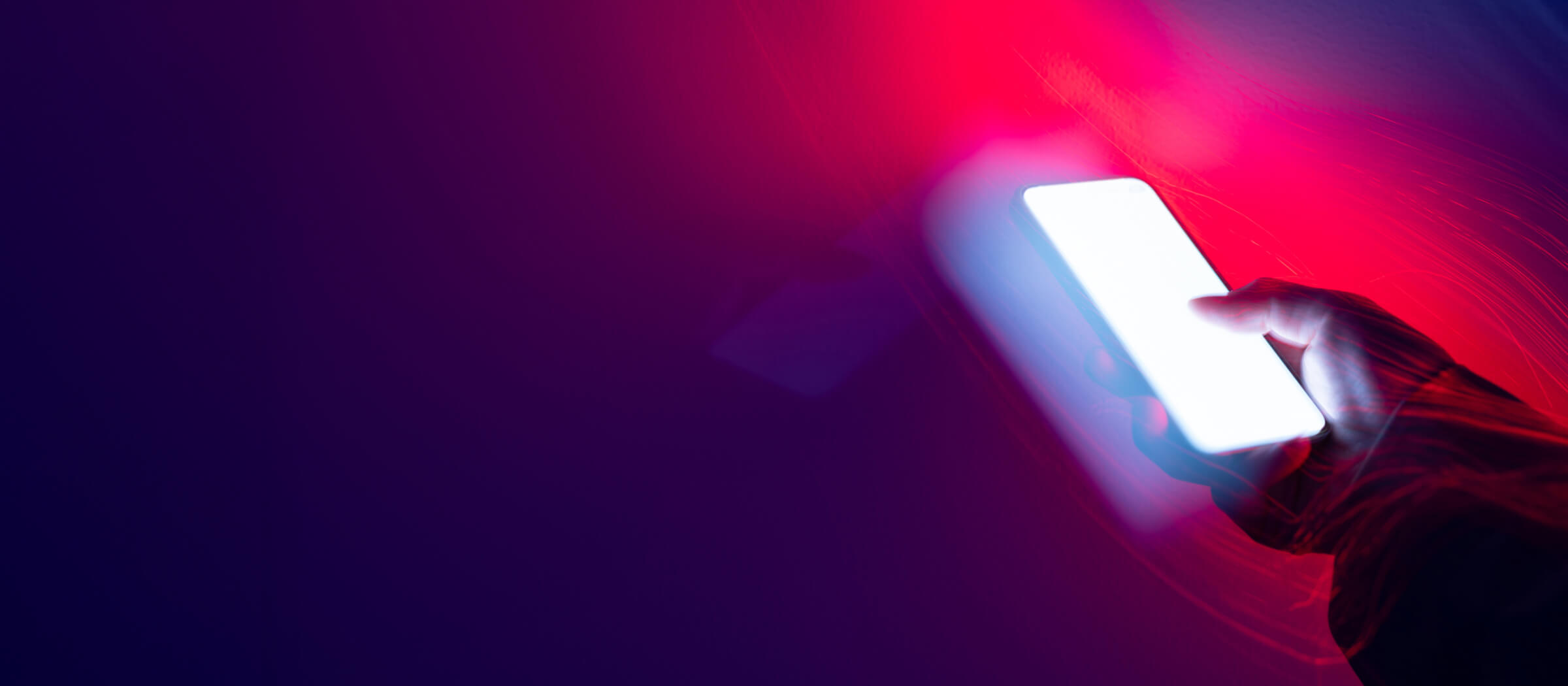 Es wurde eine erhöhte Anzahl von Schadensfällen festgestellt. Betroffen sind vor allem Kundinnen und Kunden, die das chipTAN-Verfahren nutzen. Verschwommener Hintergrund in Lila-Rot mit einer Hand die ein Smartphone hält.