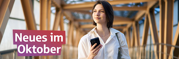 Neues im Oktober - Frau mit Smartphone steht auf einer Bahnbrücke.